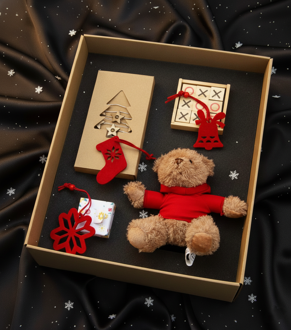 Set cadou de Crăciun StoryBox cu ursuleț de pluș, decorațiuni roșii, lumânare și cutie elegantă, prezentate într-un decor festiv pe fundal negru.
