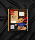 Set cadou StoryBox Miracolul Crăciunului cu ursuleț de pluș, decorațiuni roșii și suport foto, prezentat în cutie elegantă pe fundal negru satinat.